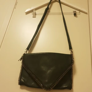  - Läderväska , i mörkgrönfärg. Med silverdetaljer. Helt ny