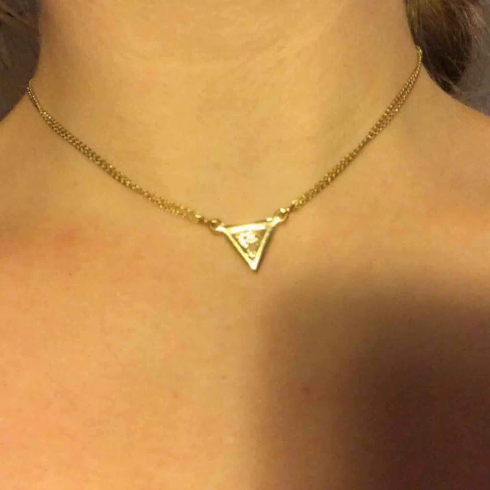 Choker halsband i guld med trekant. Halsbandet kan som längst bli 43 cm och som kortast 30 cm. Köparen betalt frakten. Accessoarer.