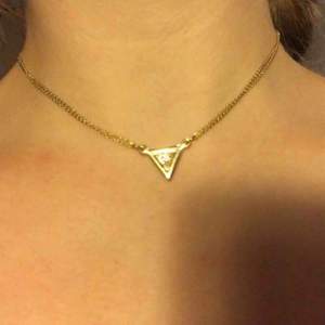 Choker halsband i guld med trekant. Halsbandet kan som längst bli 43 cm och som kortast 30 cm. Köparen betalt frakten