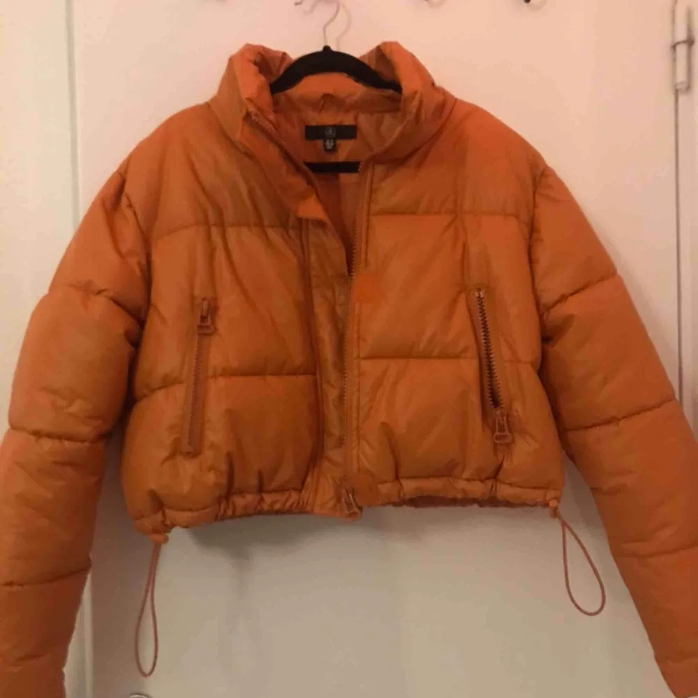 Orange croppad puffer jacket med dragsko i nederkant. Jackor.