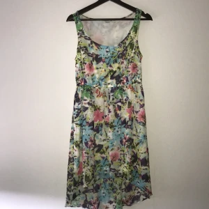  - Fin blommig klänning i färgerna grönt rosa lila turkost. Jätte skönt tunt material och ett fint fall med en insydd underklänning. Består av 100%polyester. Betalning sker via Swish och kunden står för frakten. 