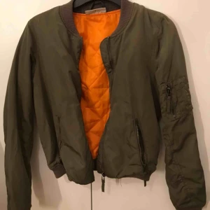  - Säljer en grön bomberjacka från Noisy May. Köptes för ungefär ett år sedan. Den har bra skick. Dragkedjeförsedda fickor. Muddar i ärmslut samt nederkant.