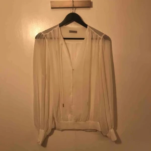  - Vit blus. Tunn med snörning i halsen. 