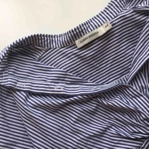  - Blårandig, lite kortare skjorta med ”knytning” där fram. Passar M/L. Kostar 60kr inklusive frakt!