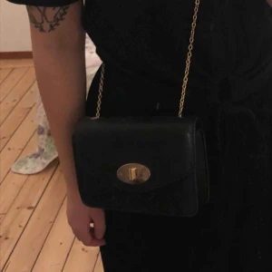  - Finfin stilren väska med gulddetaljer! Kedjan går att stoppa in för att skapa en handväska istället för axelväska. Köpt på glitter och använd endast en gång. Möts upp i Sthlm, annars står köparen för frakten. 💛