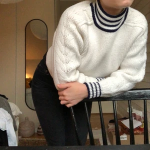 Stickad polotröja - Vit stickad polotröja med blårandigt på krage och längst ner på ärmarna. Köpte den second hand, men har själv inte använt den något. (PS. Har ej hunnit väga klädesplagget ännu, därför är priset för frakt inte helt säkert)