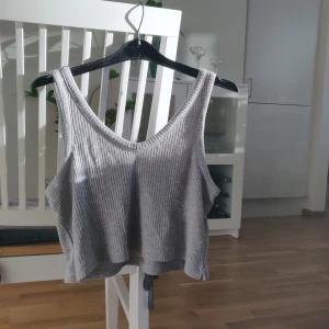 Croppad linne Bikbok stl XS - Ett ljusgrått croppat linne från Bikbok i storlek XS. Fraktkostnaden tillkommer.