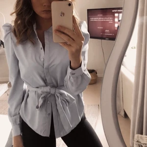 Blus/skjorta  - Ljusblå blus/skjorta med band i midjan och knappar. Använd en gång. Nypris 499