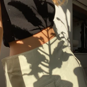 Vit Skinnkjol  - Vit skinnkjol med coolt prickigt mönster nertill. (Prickarna är små hål i lädret). Aldrig använd då den inte passar i storleken. Snedskuren med en tenniskänsla, snygg till boots eller enkla sneakers:-) 