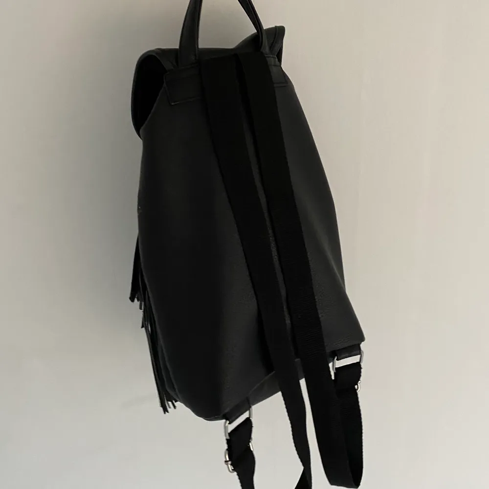 Svart liten supersnygg ryggsäck med svarta fransar i fint skick, passar verkligen till allt🤩. Väskor.