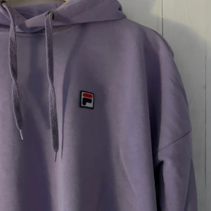 Fila Hodie - Fin ljuslila hodie från Fila i tunnare tyg. Använd men i bra skick, köpt från Junkyard. Ganska stor för att vara storlek s, Säljer då den inte kommer till användning.