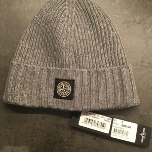 Stone island mössa. - Storlek L i barnstorlek. Nypris 699 kr bud från 499kr. Aldrig andvänd 10/10 skick. Prislapp finns kvar. Köpt på nk. Färg grå.