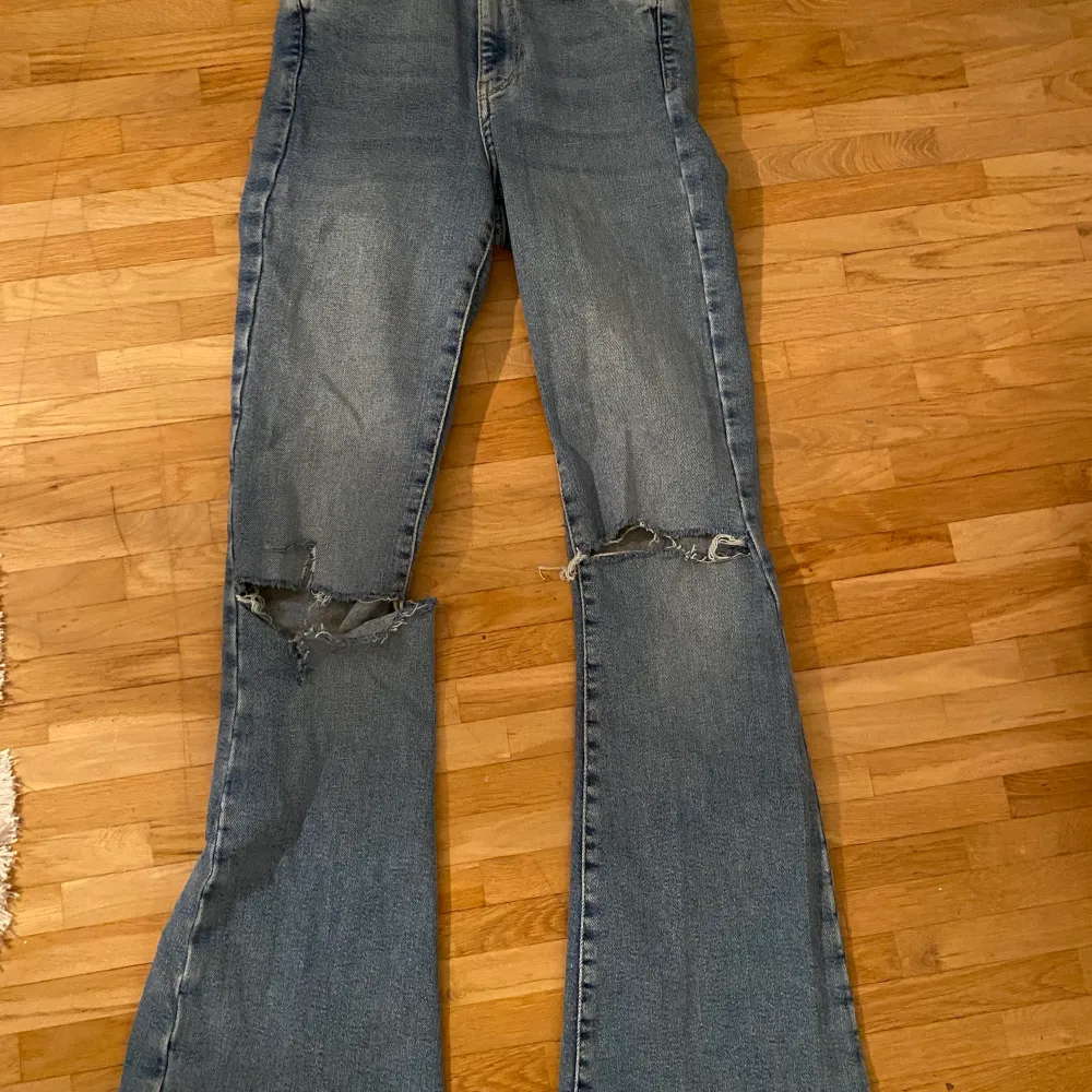 Utsvängda jeans med hål i knäna. Köpta från Gina Tricot. Använda några gånger, jättesköna och stretchiga. Strl 34.. Jeans & Byxor.