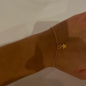 Armband, smycken  - I06. Jättefint armband i guld med en stjärna på, glöm inte att 10% av vinsten går oavkortat till organisationen kvinna till kvinna.