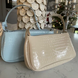 Axelväska - 2 superfina axelväskor i olika färger. Köpte för ett tag sen och har endast använt den beiga nån gång medans den blåa aldrig är använd.                                  1 väska: 70kr.                                                                       2 väskor: 130kr