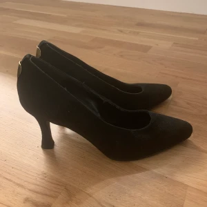 Klackskor i svart sammet - Klackskor i svart sammet med gulddetaljer baktill. Italienska. Knappt använda. Hela klacken och underdelen ser väldigt fin ut. 