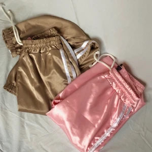 ✨Sporty satin pants🌸 - Två par i modell likadana sportiga byxor i satin-material💕ett par är ljust rosa och det andra är i en guld nyans💕muddar vid ankeln och highwasted💕reglerbara i midjan💕säljs separat eller tillsammans💕frakt ingår inte utan kostar 42kr💕skriv om det finns några frågor💕
