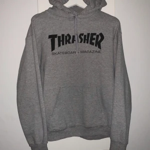 Thrasher Hoodie - Grå Thrasher Hoodie i storlek S, normal använt skick utöver två väldigt små fläckar (se andra bilden). Köpare står för frakt 66kr. Endast seriösa köpare, tack! 450kr eller bud!