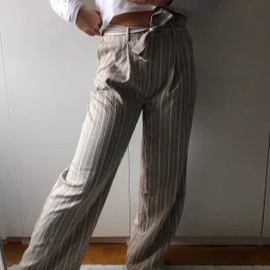 Randiga byxor - Beigevit randiga byxor från na-kd. Byxornas färg visas bäst på andra bilden. Säljer pga använder inte.