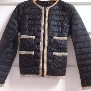  - Tunn dunjacka/lättviktsjacka från Mango. Svart med beiga detaljer. Fyra fickor och knäppning med dragkedja. Mycket gott skick, använd vid två tillfällen.