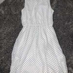 En fin vit klänning med blå prickar på, längden är ungefär till knäna.