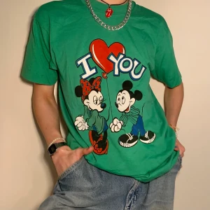 Grön retro 80s Minnie & Mickey Mouse graphic t-shirt - Lugn grön 80s retro graphic tee/t-shirt med Musse och Mimmi pigg tryck + den perfekta baggy siluetten ☎️ Görgulligt tryck med Musse hållande i en hjärtformad ballong som blir hjärtat i frasen ”I love you” och Mimmi! Inte nog med att denna t-shirt går att matcha med allt i och med dess lättmatchade färger utan både Musse och Mimmi har dom snyggaste outfitsen på hela denna appen?!  Alla priser är inkl. frakt och alla plagg tvättas innan de skickas iväg