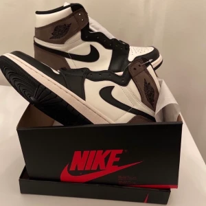 Nike AJ1 Retro High OG Mocha ☕️ - ÄKTA. Helt nya och aldrig använda. Storlek: 41 EU. Extra laces följer med och box.                                                                             Kan mötas upp i Sthlm city eller frakta (kunden står för frakt). Kvitto finns, lägg ett bud!!                                         OBS! Priset kan diskuteras vid SNABB affär :) 