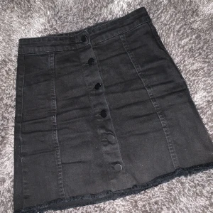 Jeans kjol - En svart jeans kjol med knappr fram.