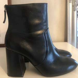 Svarta boots från pull and bear - Ett par snygga blanka boots med silver detalj på baksidan. Storlek 39. Köpt från pull and bear. Använd endast en gång och tyvärr så har jag inte någon användning av dessa. 
