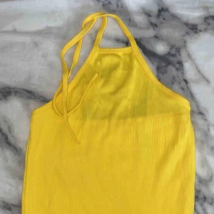  - En crop top som är gul som man knyter där bak 