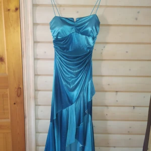 Glansig glittrig klänning  - Volanger, glitter och olika skärning på kjolen. Sitter väldigt snyggt på. Något j.Lo skulle burit i början av 2000...