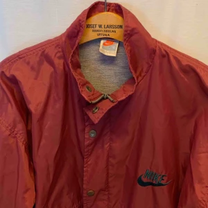  - Vintage Nike Crimson Nylon Bowerman Coach Jacket. Jackan är i mycket gott skick, Storlek S men det är baggy fit / oversized   Kan hämtas i Uppsala eller skickas mot fraktkostnad.