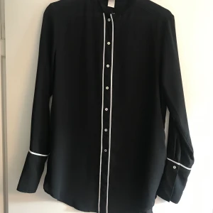 Snygg skjorta - Svart blus med vita ränder från H&M conscious. 100% polyester. Fint använt skick. Betalas med swish. Frakt ca 50kr 