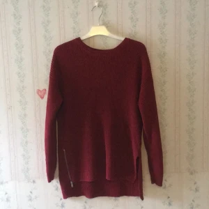  - Mörkt rosaröd stickad tröja med dragkedja på ena sidan och en kort slits på andra. Använd ett fåtal gånger. Köparen står för frakten.