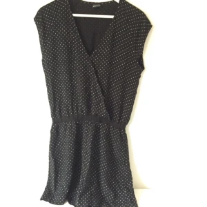  - Svart jumpsuit / playsuit med vita prickar. Liten tryckknapp i fram. Resår i midjan och 'shorts' med sidofickor.  Använd en gång, nyskick,  Kan posta eller mötas upp i Stockholm. 