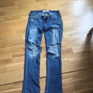 - Säljer dessa blåa bootcut byxor med hål på knäna från hollister. 