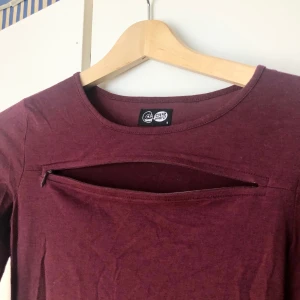 Tight klänning - Cool klänning från Ceap Monday med dragkedjor vid armbågarna och ovanför bröstpartiet. Kan välja om dem ska vara öppna eller ej. Använd 1 gång. Vinröd, långärmad, figursydd  men inte supertight.