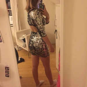  - Klänning med silvriga och svarta paljetter, perfekt nu under festsäsongen! Snygg öppning i ryggen (där bh-n inte syns). Passar XS-S. Använd endast en gång.