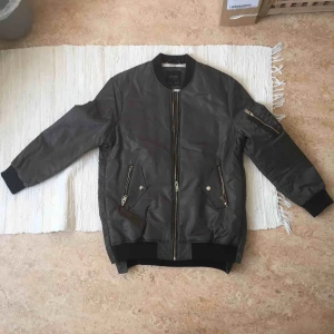  - Snygg grön-grå bomberjacka från Zara. Rutat mönster på ryggen & gulddetaljer/gulddragkedja. Storlek M och den är lite oversized. Säljer för att jag aldrig använder den. Köparen står för frakt. Skriv om du har någon fråga :)