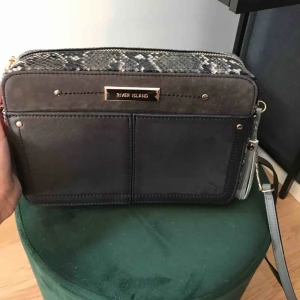 River Island väska  - Grå väska med ormskinnsdetaljer från river island. Har knappt använt den men den är så fin! 