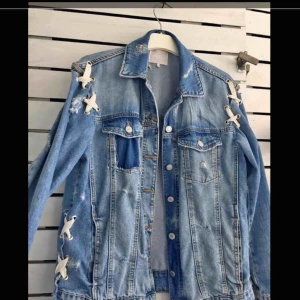  - Jeansjacka med slitningar och snören vid sidorna, finns två fickor på utsidan men även två stora på insidan som håller mycket