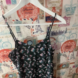  - Svart kort klänning med blommigt mönster i storlek 34.   Möts upp i Blekinge annars fraktar jag, du betalar för frakten (42kr)