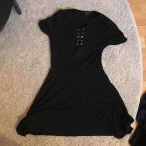  - En svartKlänning med knytnings detalj på bysten...