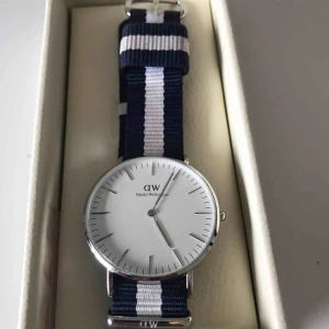  - En klocka från Daniel Wellington, aldrig använd. Marinblått och vitt band av tyg. Frakt ingår i priset 