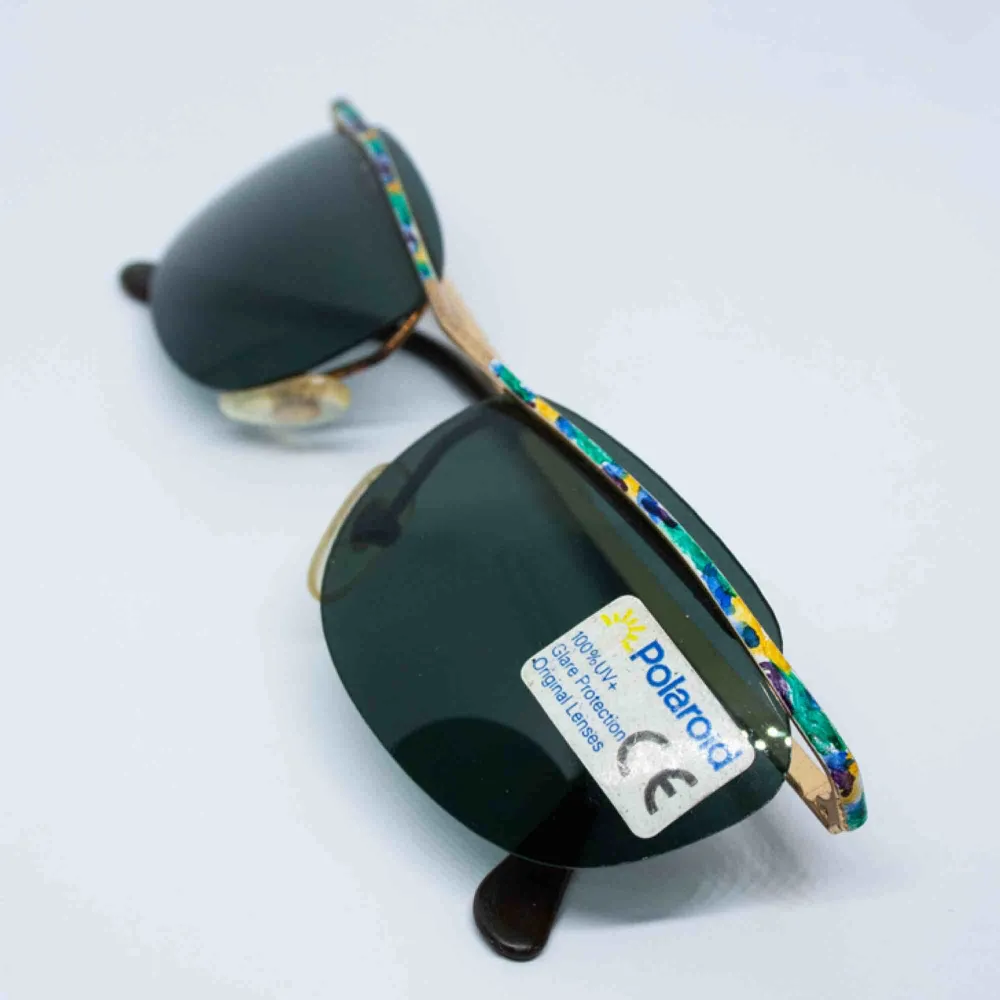Vintage Y2K 90s 00s Polaroid cyber slim sunglasses in dark green and colorful frame 100% UV+ Barely visible sign of wear, if any Measurements: Frame: 13.5 cm width: 3.8 cm temple: 13 cm Free shipping. Accessoarer.