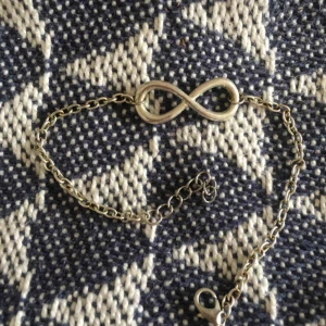  - Fotlänk i silvrig färg med ett evighetstecken på. För fler bilder/frågor hör av dig! 