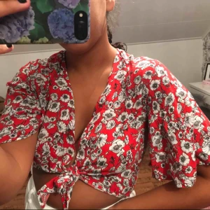  - En kortare topp/skjorta i rött med blommor på, knytbar🤩❣️