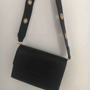  - Svart väska, band - 90 cm. Har två fack inuti. Väskan är helt oanvänd och har inga märken eller skråmor. Köpt för 300 kr. 🥰🥰 Kontakta för mer bilder eller info!