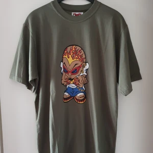 Vintage t-shirt - Vintage grön t-shirt med tryck i storlek L. I jättefint skick, har dock en liten prick på huvudet där lite tryck lossnat men inget man ser mycket (kan skicka närmre bilder om det önskas). Fraktkostnad blir 45kr. Ni får jättegärna kommentera bud vid intresse, med höjning på minst 5kr 😊 sluttid torsdag kl 18