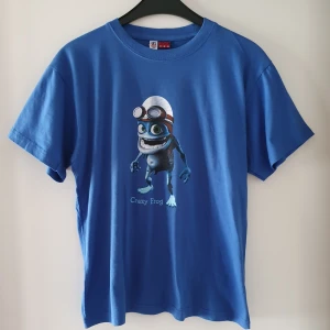 Vintage t-shirt Crazy Frog - Vintage blå t-shirt med Crazy Frog. Storlek 164 men passar ca storlek XS/S och även kanske liten M. Fraktkostnad blir 45kr. Kommentera jättegärna bud om du är intresserad, med höjning minst 5kr 😊 sluttid torsdag kl 18